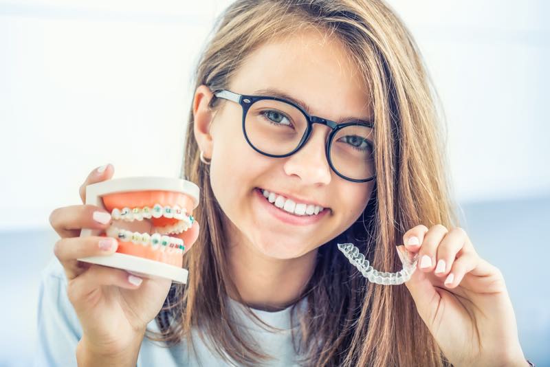 Teenager mit Zahnspangenmodell und Schiene